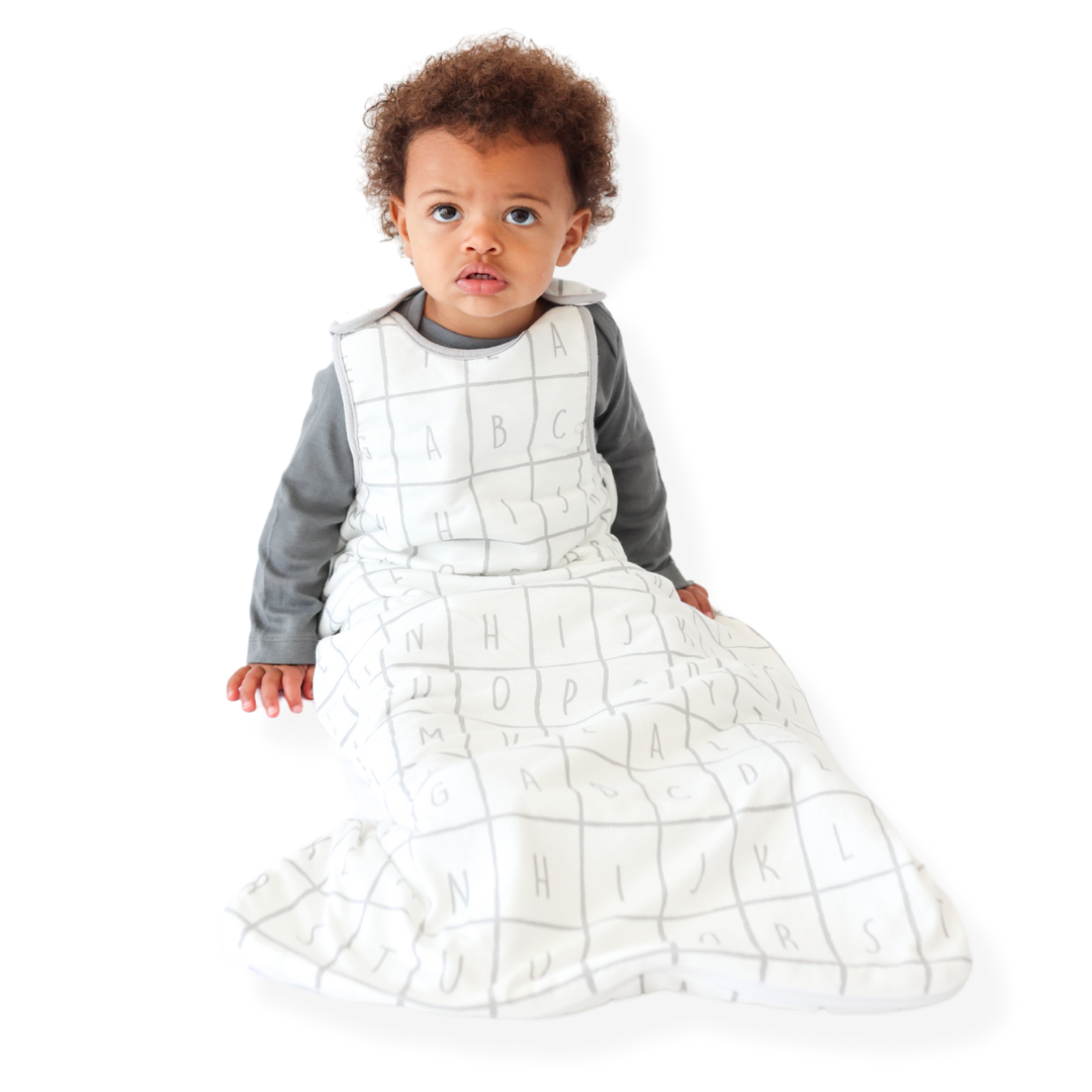 A baby sitting down comfortably in a Tealbee Dreambag 1.2 TOG, highlighting the perfect combination of warmth, coziness, and freedom of movement for a happy, restful sleep.