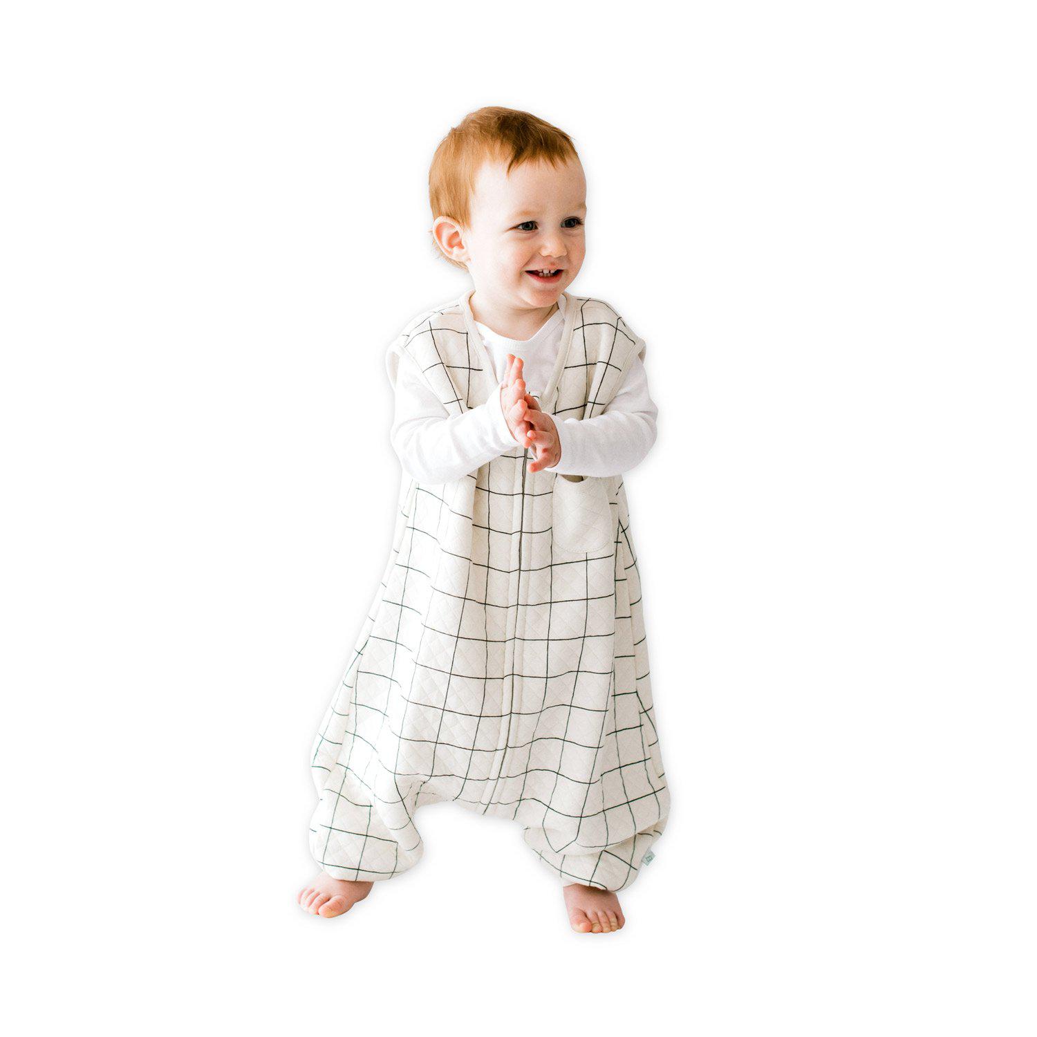 A baby standing comfortably in a Tealbee Dreamsuit, featuring buttery soft and cozy fabric made of 70% Bamboo Rayon and 30% Organic Cotton. Designed as a sleep sack with feet for walkers, ensuring both comfort and safety.