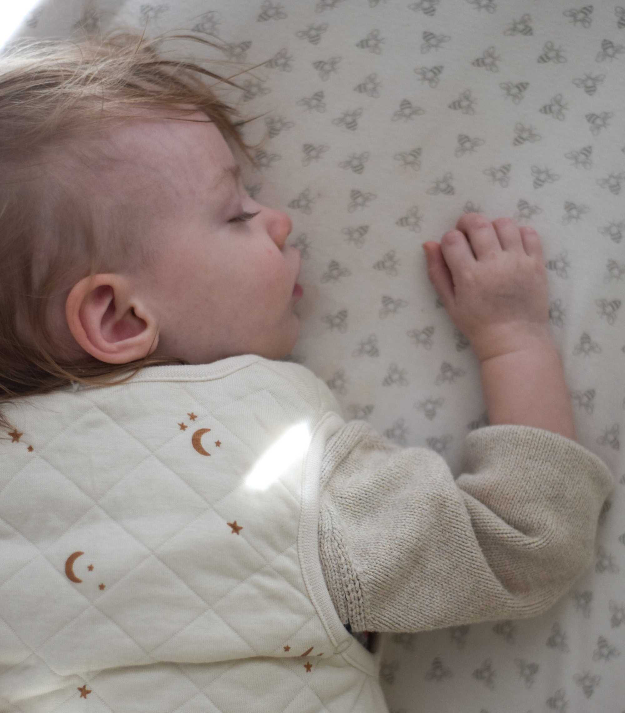 Baby lying on a crib wearing a tealbee dreambag