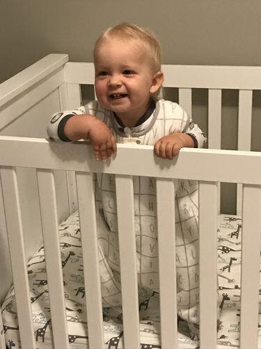 Child in a crib wearing tealbee dreamsuit in alphabet print