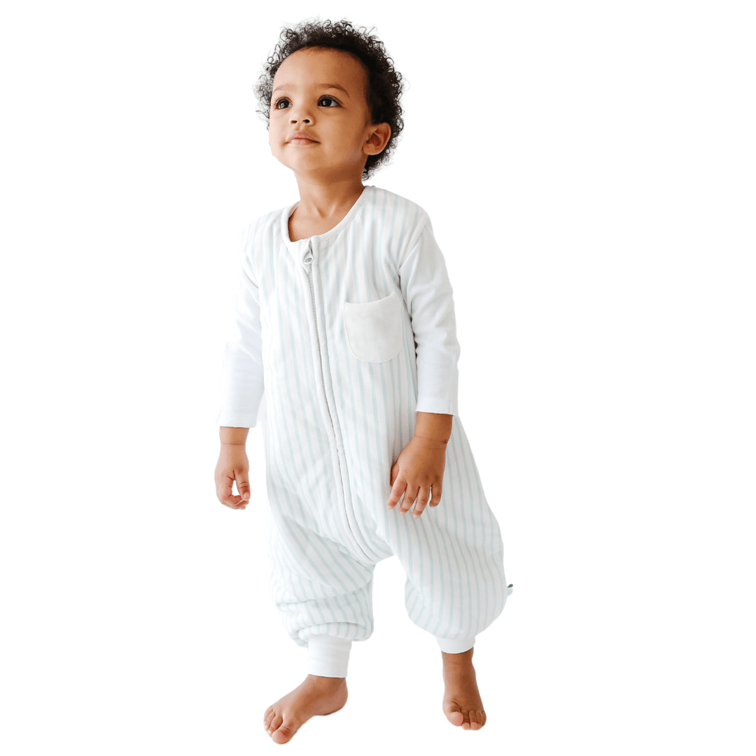 A baby standing comfortably in a Tealbee Dreamsuit, featuring buttery soft and cozy fabric made of 70% Bamboo Rayon and 30% Organic Cotton. Designed as a sleep sack with feet for walkers, ensuring both comfort and safety.