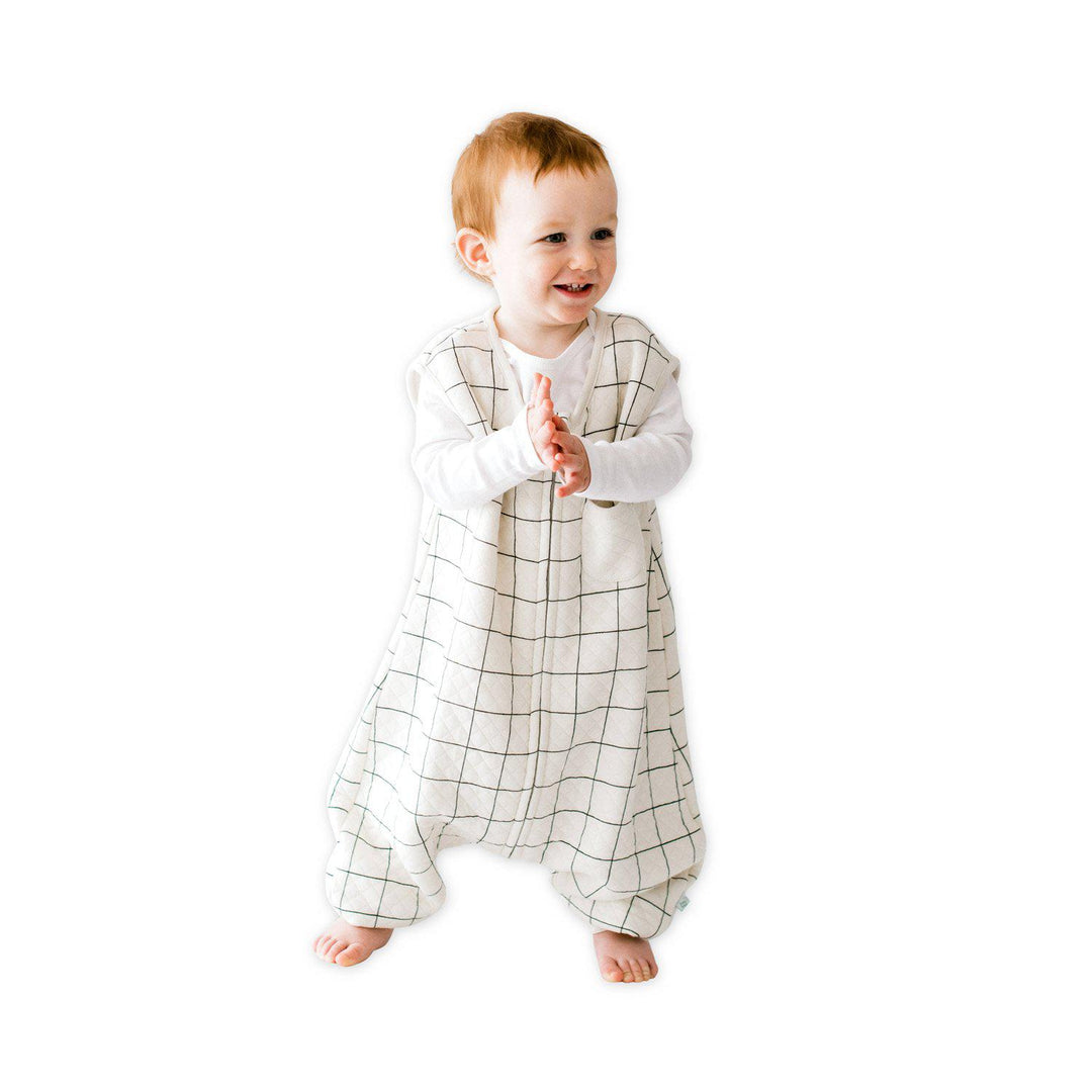 A baby standing comfortably in a Tealbee Dreamsuit, featuring buttery soft and cozy fabric made of 70% Bamboo Rayon and 30% Organic Cotton. Designed as a sleep sack with feet for walkers, ensuring both comfort and safety.