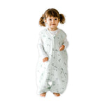 A baby standing comfortably in a Tealbee Dreamsuit, featuring buttery soft and cozy fabric made of 70% Bamboo Rayon and 30% Organic Cotton. Designed as a sleep sack with feet for walkers, ensuring both comfort and safety.